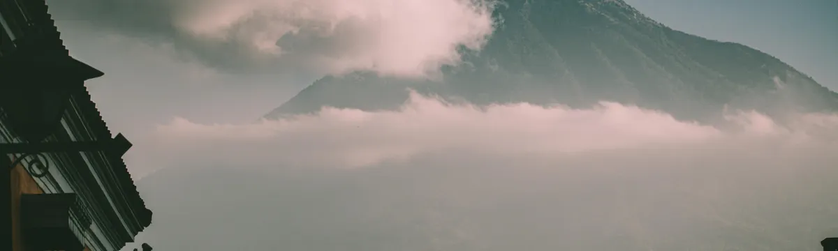 גואטמלה: Dramatic view of a volcano with clouds over Ciudad de Guatemala's architecture.