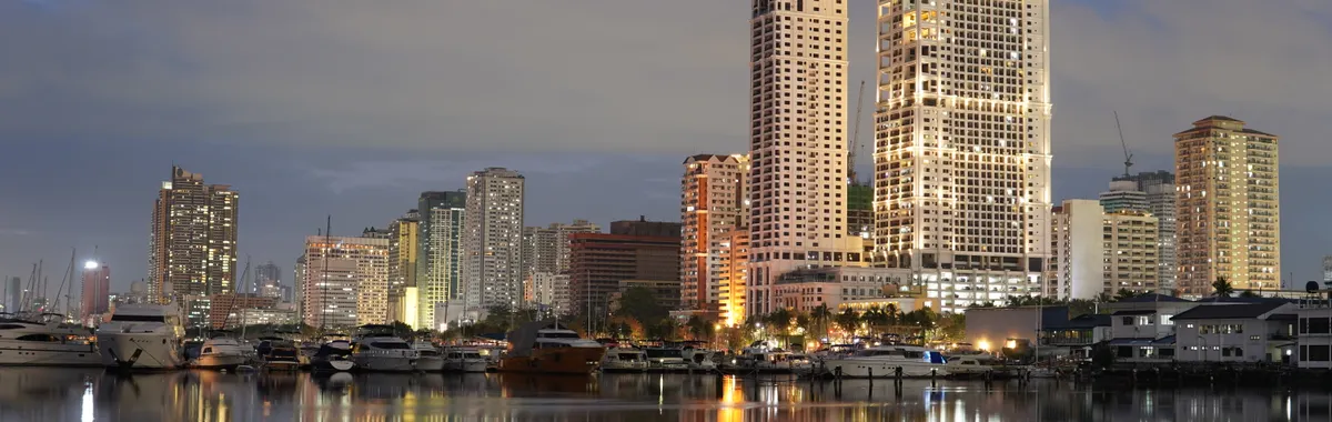 Stunning twilight view of Manila's skyline reflecting on a calm body of water, featuring tall buildings and a serene atmosphere.