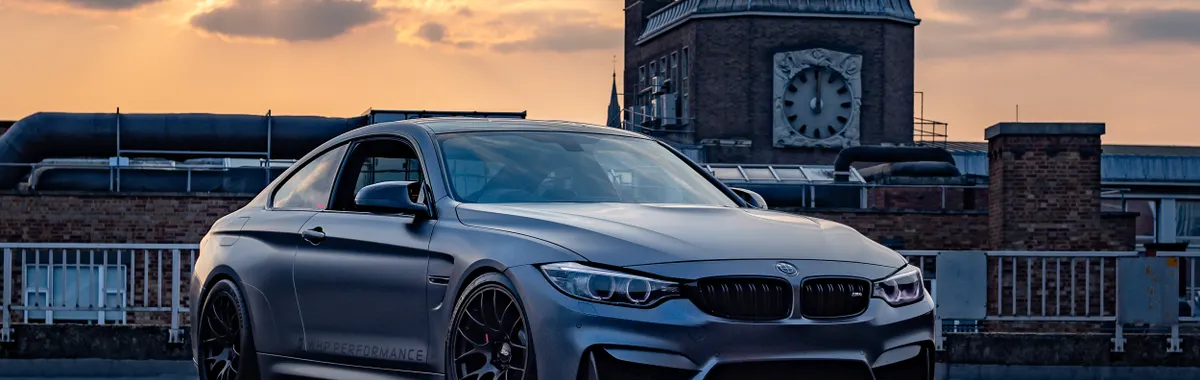 A sleek luxury sports car parked on a rooftop at sunset with industrial backdrop in Leicester, UK.