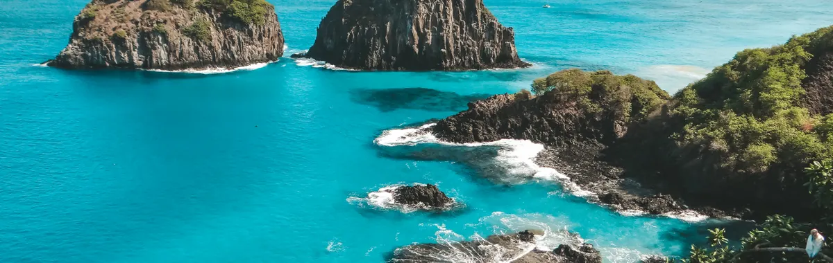 A breathtaking aerial view of the rocky coastline and blue waters of Fernando de Noronha, Brazil.