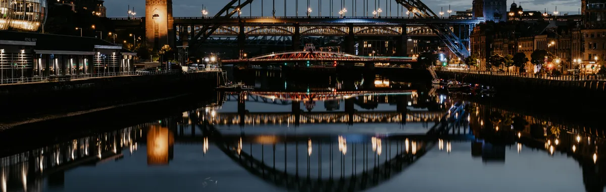 Stunning night cityscape of Newcastle's Tyne Bridge reflecting in the river.