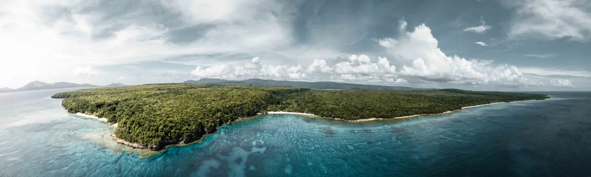 ונואטו: A breathtaking aerial view of the lush green coastline of Vanuatu, surrounded by crystal clear waters.