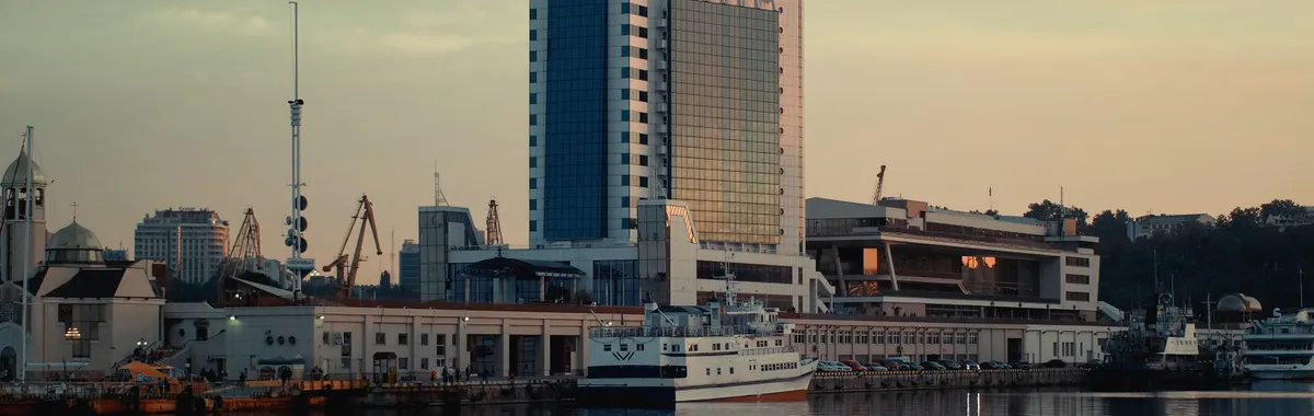 Scenic view of Odesa Sea Port and modern architecture reflecting in water during sunset.