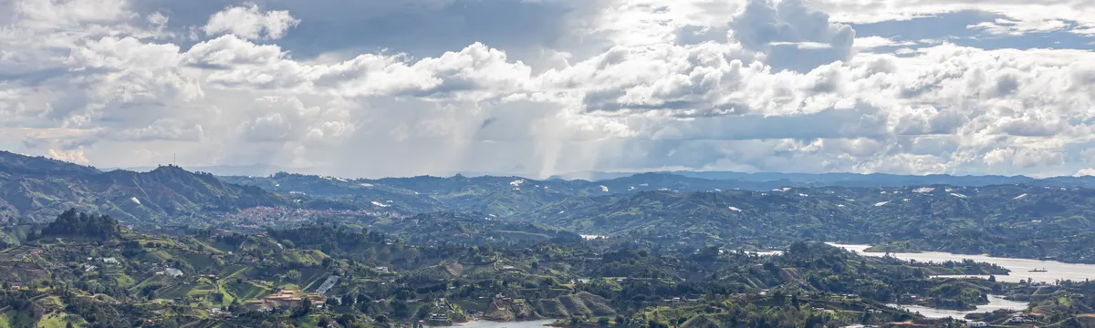 קולומביה: A breathtaking aerial view of the lakes and rolling hills in Guatapé, Antioquia, Colombia, under a dramatic sky.