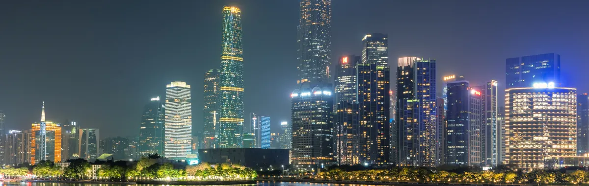 Illuminated skyscrapers of Guangzhou reflecting on the water under a night sky.