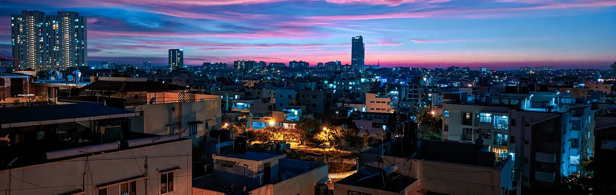 Stunning view of Bengaluru cityscape illuminated at dusk, showcasing modern architecture under a vivid sunset sky.