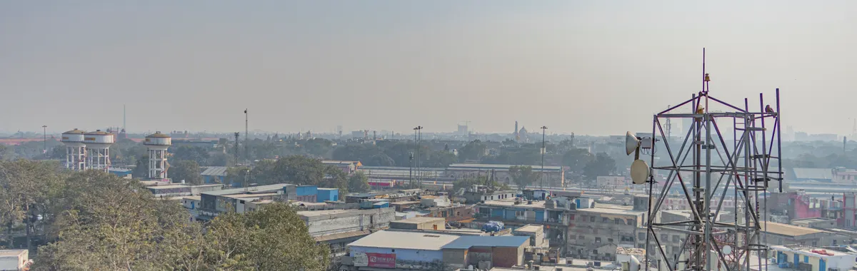 Aerial view of urban buildings and trees with a telecom tower in New Delhi, India.