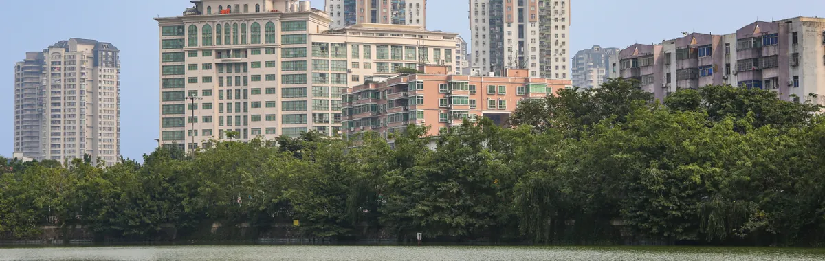 Cityscape of Hefei showcasing modern architecture and a tranquil pond reflection.