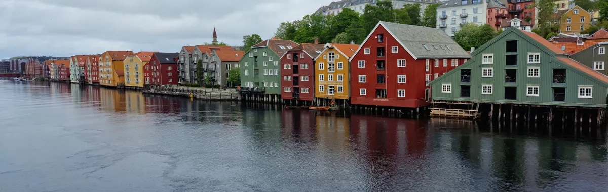 A vibrant view of colorful waterfront houses in Trondheim, Norway under overcast skies.