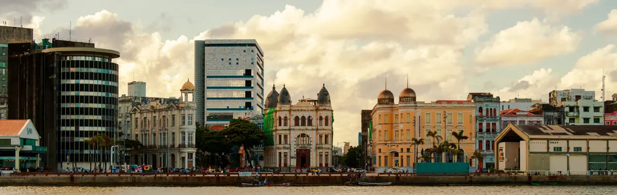 Scenic view of Recife's waterfront architecture showcasing historic and modern buildings under a partly cloudy sky.