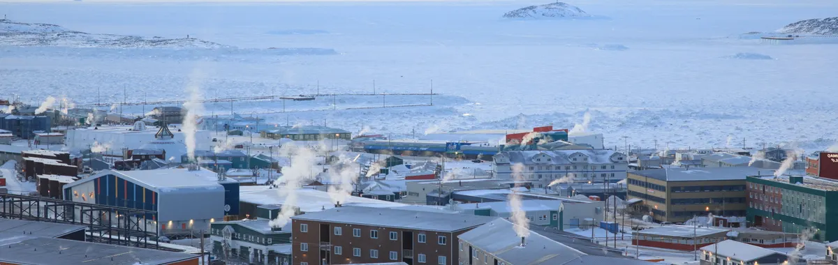 A panoramic winter view of Iqaluit, Nunavut, capturing arctic architecture in a snowy landscape.