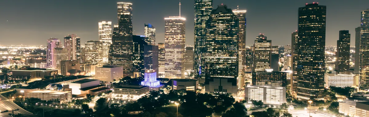 Stunning aerial view of Houston's illuminated skyline featuring skyscrapers and highways at night.