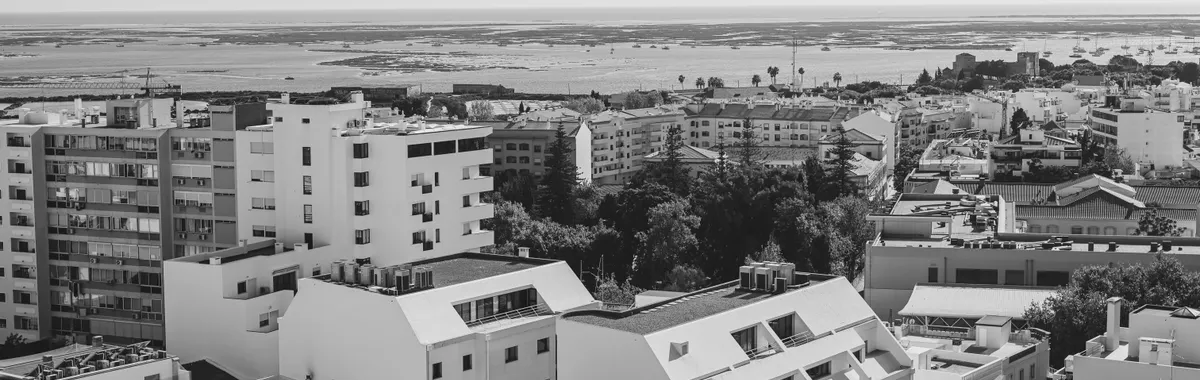 Black and white aerial view of Faro's urban landscape with the Atlantic in sight, capturing Portugal's coastal charm.