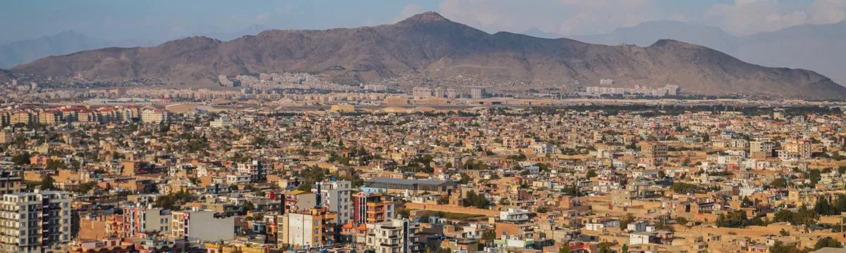 אפגניסטן: Aerial cityscape of Kabul, Afghanistan with mountains in the background.