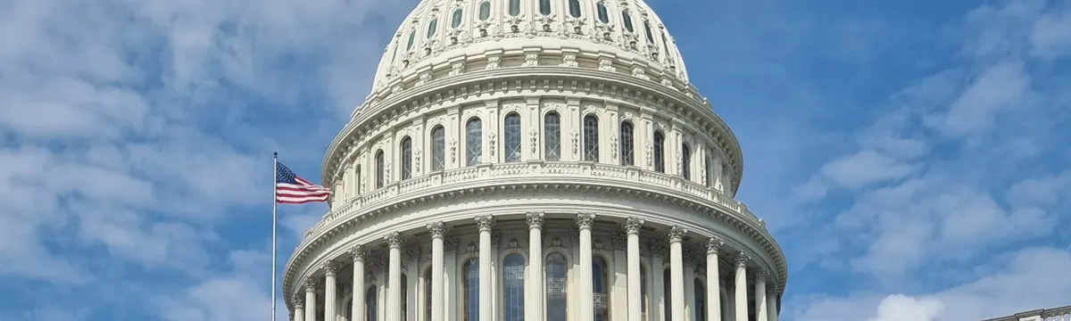 ארצות הברית: A striking view of the US Capitol dome with flag and blue sky in Washington, DC.