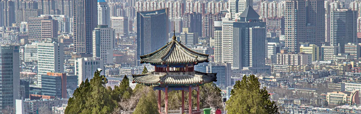 Elevated view of Jinan's skyline with traditional Chinese pavilion in the foreground.