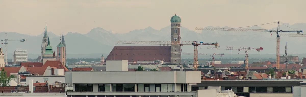 Scenic view of Munich skyline featuring the Frauenkirche and surrounding architecture at sunset.