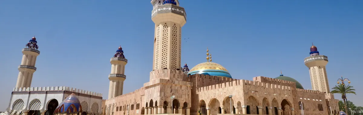 The Grand Mosque of Touba, Senegal, with its iconic minarets under a clear blue sky, showcasing Islamic architecture.