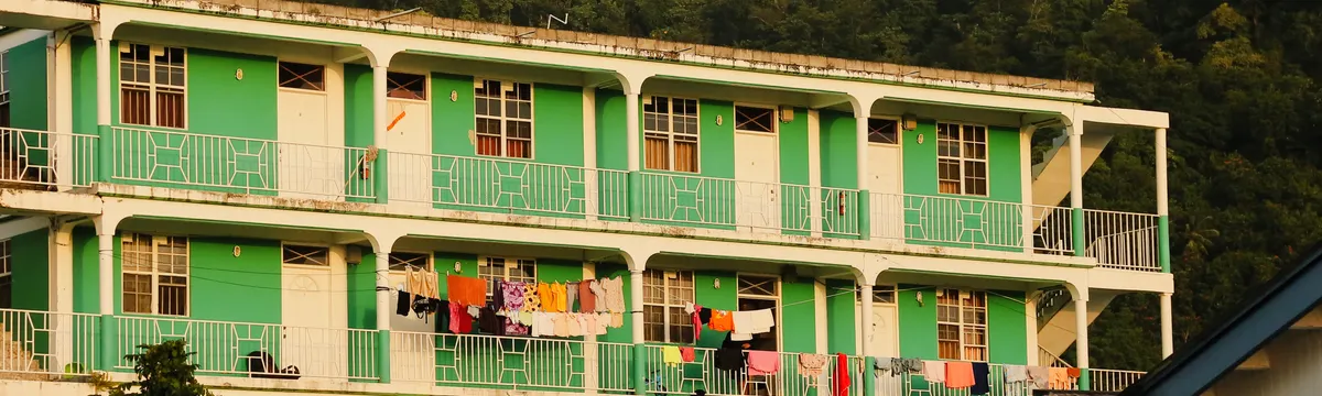 דומיניקה: Vibrant apartment building with laundry on balconies in Portsmouth, Dominica, during sunset.
