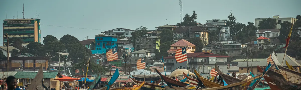 ליבריה: Vibrant scene of fishing boats and urban skyline in Monrovia, Liberia.