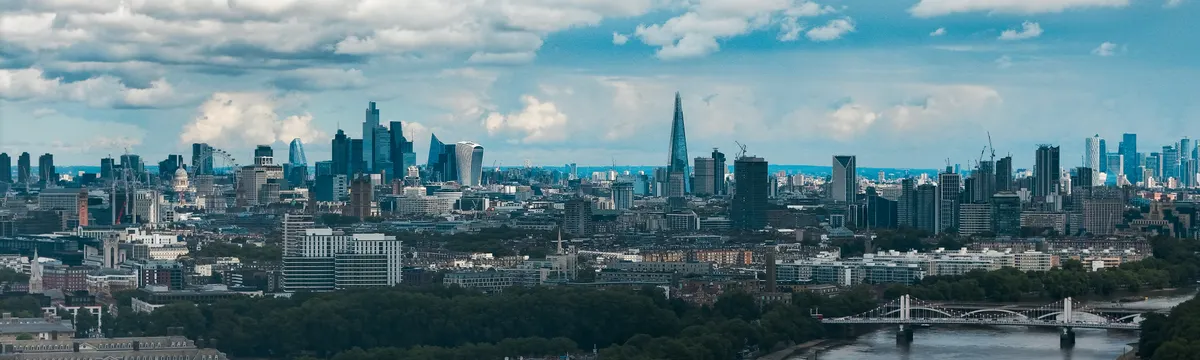 בריטניה: Wide-angle view of London's modern skyline and River Thames under a dramatic sky.