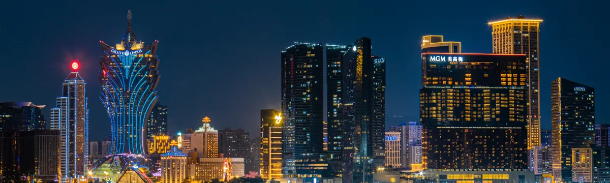 מקאו: Elegant night view of Macau skyline featuring iconic illuminated hotels and a lit bridge over water.