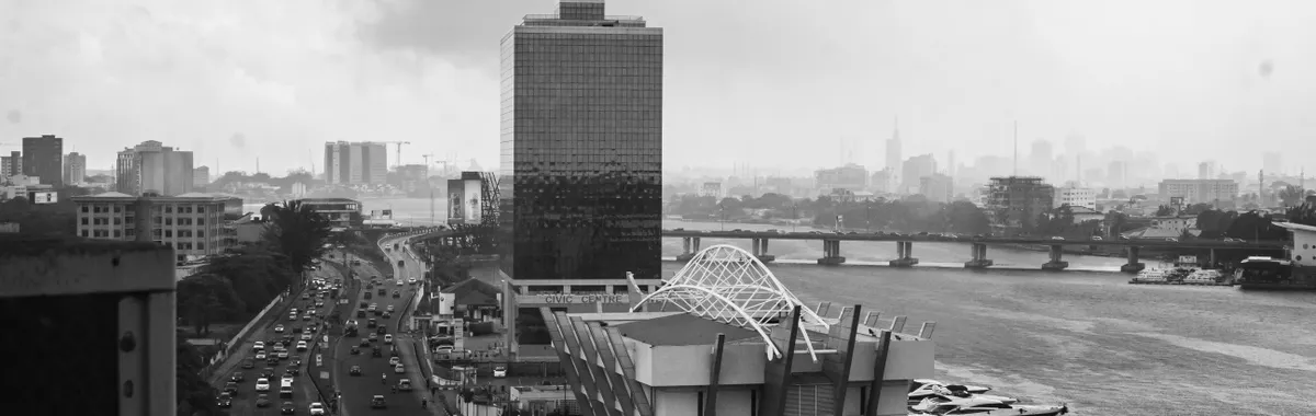 Black and white cityscape of Lagos with a prominent architectural structure and busy road.