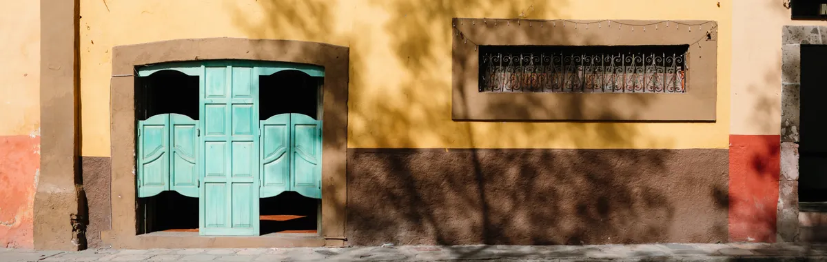 Yellow Mexican bar facade with turquoise doors in San Miguel de Allende.