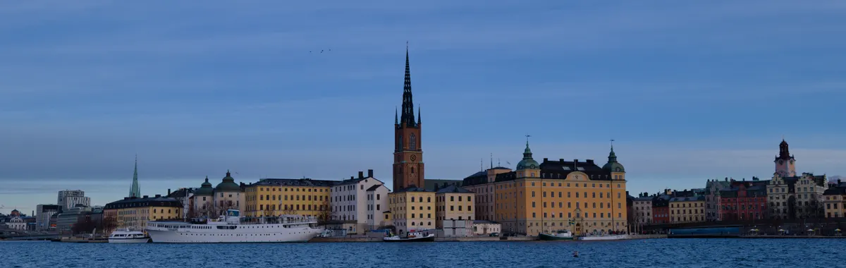 Skyline of Stockholm with historic architecture reflecting on water under a clear sky.