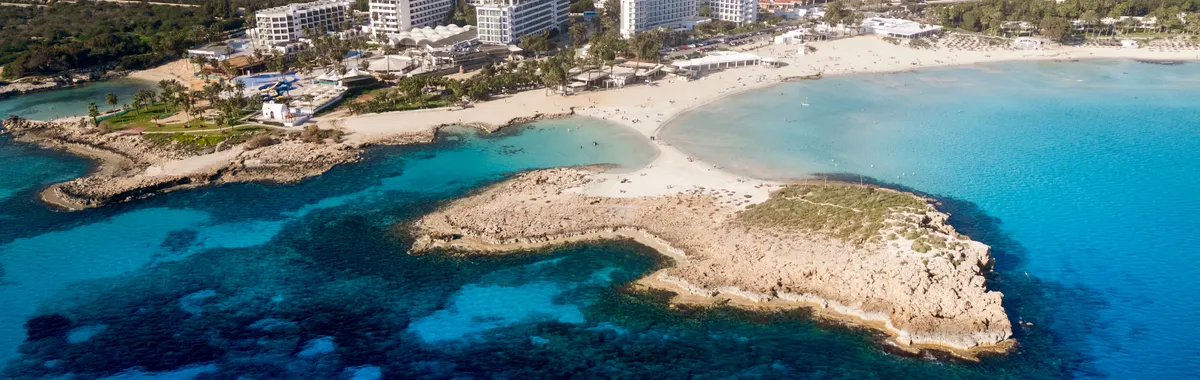Aerial view of Ayia Napa's pristine coast with turquoise waters and resort buildings.