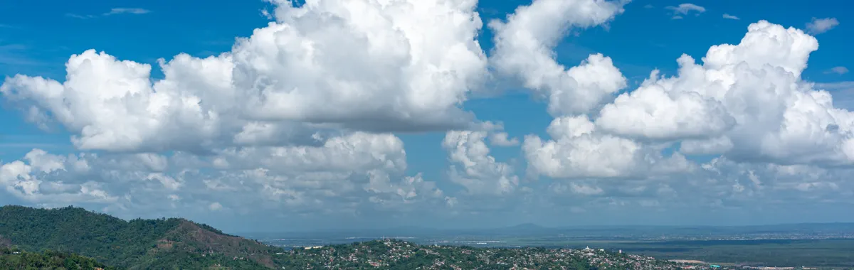 Breathtaking aerial view of Port of Spain with lush hills and clear skies, showcasing Trinidad's vibrant cityscape.
