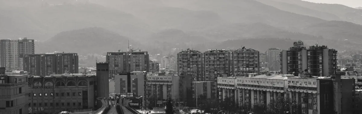 Aerial view of Skopje cityscape with distant mountains and urban architecture.