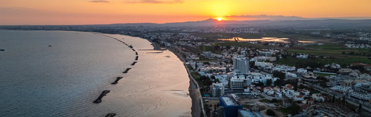 Aerial view of Limassol's coastline during sunset, showcasing the vibrant city and serene sea.