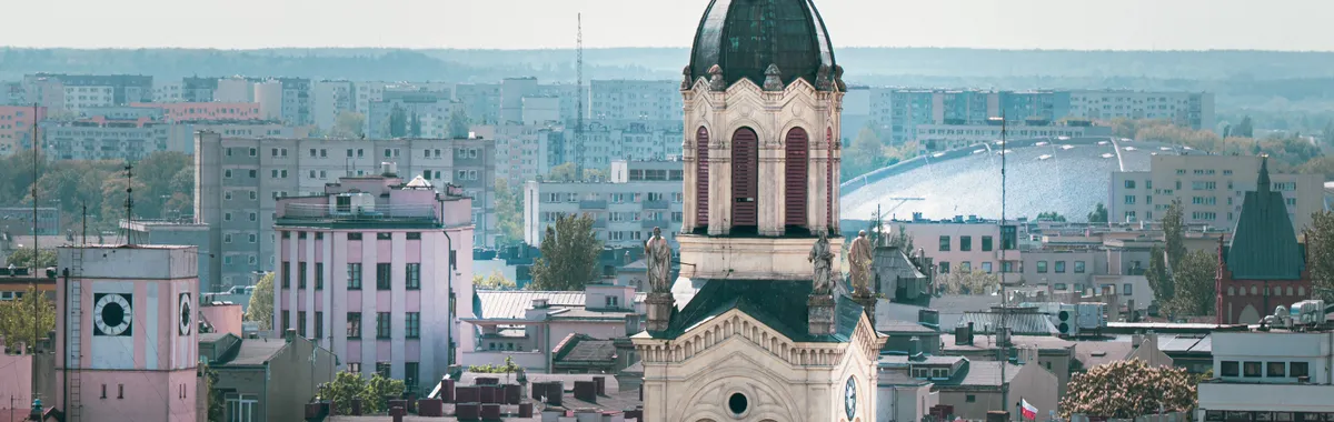 Explore the blend of historic and modern architecture in Łódź, Poland, showcased by this beautiful church tower amidst the city skyline.
