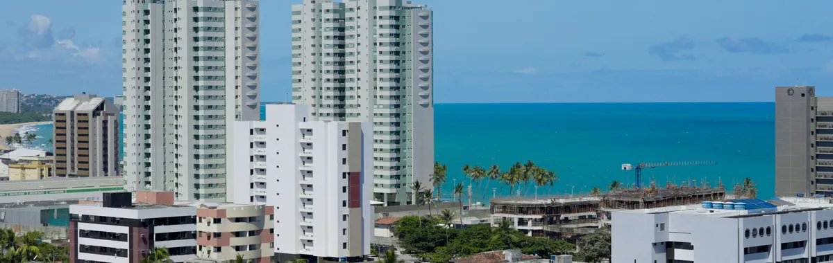 High-rise buildings in Maceió offer a stunning view of the coastline under a clear blue sky.