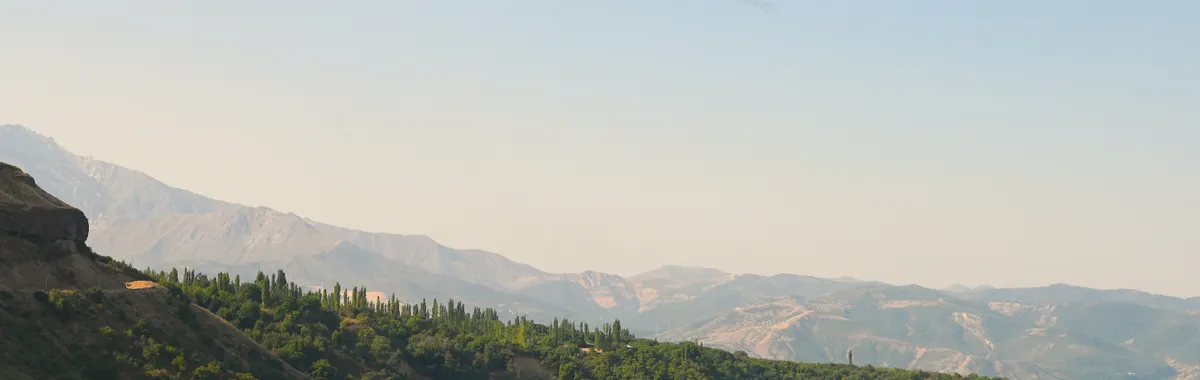 אוזבקיסטן: Tranquil view of a mountain lake surrounded by lush green hills in Tashkent Region, Uzbekistan.