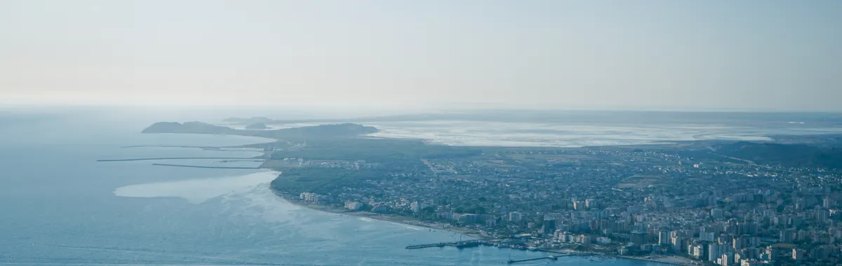 Stunning aerial view of Vlorë, Albania with coastline and cityscape under a clear blue sky.