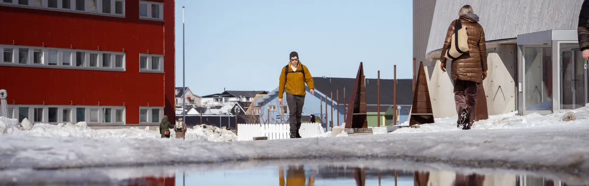 Winter scene in Nuuk, Greenland with modern architecture and reflections in water.