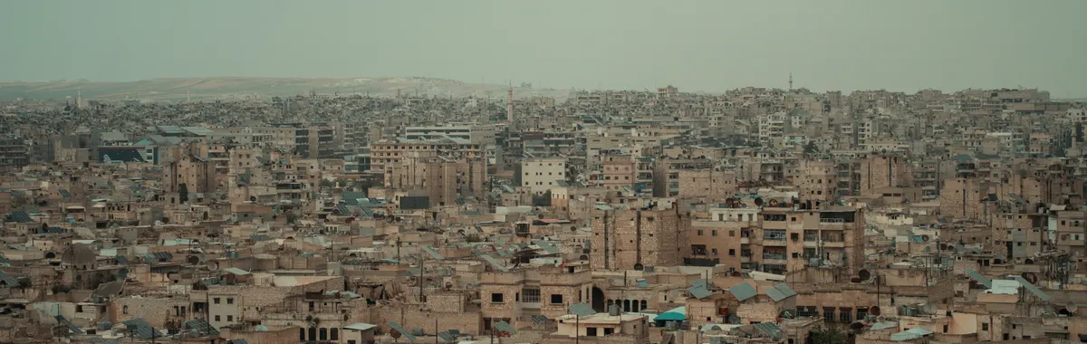 A wide aerial view of the densely packed urban landscape of Aleppo, Syria.