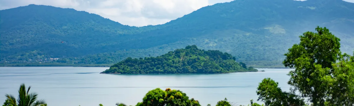 מאיוט: Beautiful landscape of an islet surrounded by the Indian Ocean in Mayotte, showcasing lush greenery and mountains.