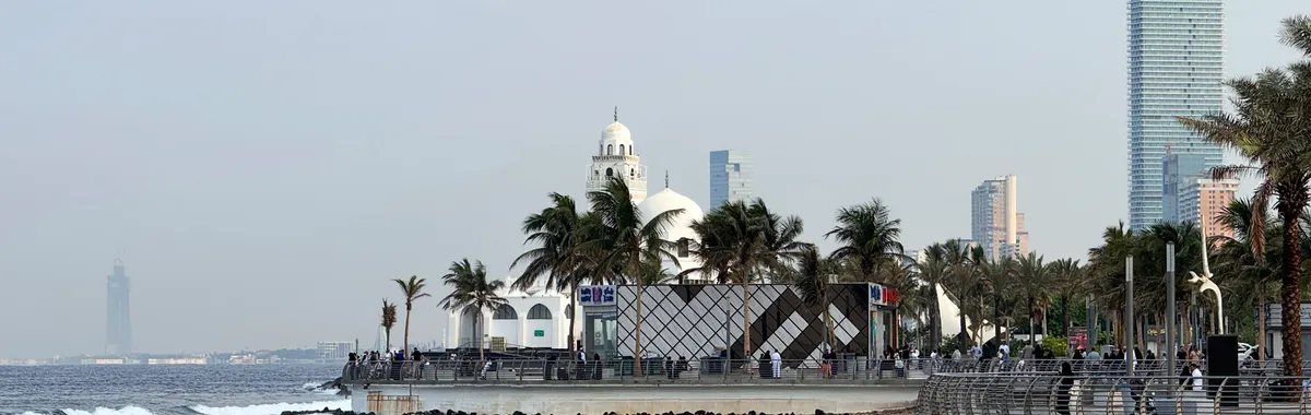 Morning view of Jeddah Corniche with palm trees and ocean waves, capturing Saudi Arabia's coastal beauty.