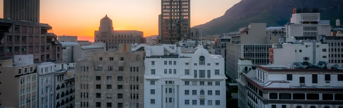 View of Cape Town's skyline at sunset with Table Mountain in the background. Vibrant, urban cityscape.