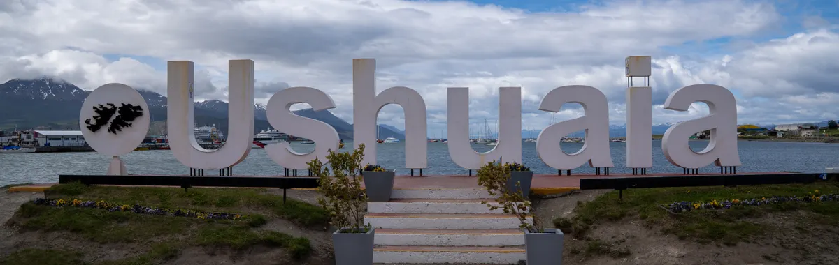 Iconic Ushuaia sign in Argentina with stunning mountain and sea view.