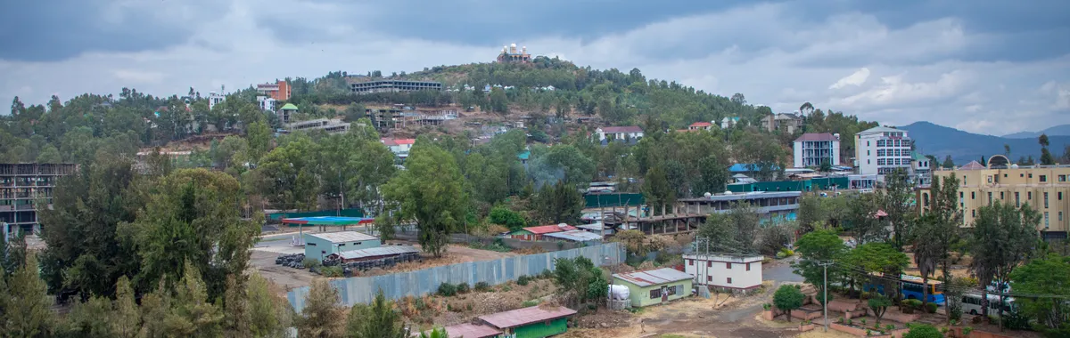 אתיופיה: Captivating aerial view of Gondar, Ethiopia with lush greenery and architecture under a cloudy sky.
