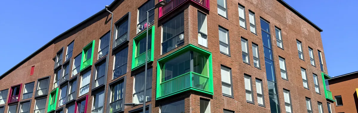 A vibrant modern apartment complex with colorful balconies in Vantaa, Finland under a clear blue sky.