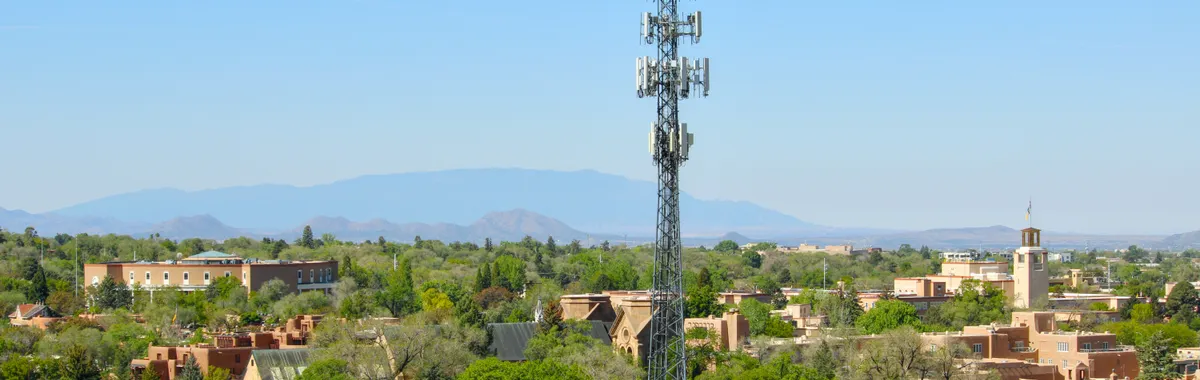 A scenic aerial view of Santa Fe, NM, featuring a cell tower and classic adobe architecture.