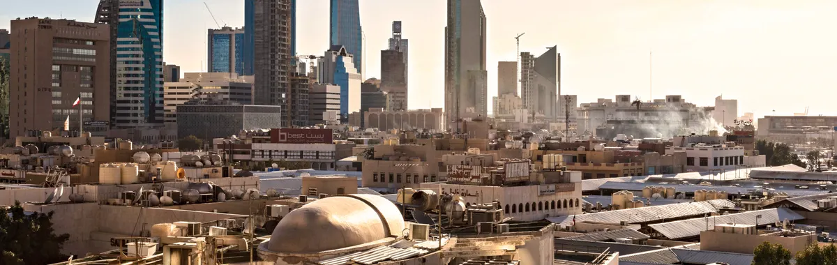 Skyline of Riyadh, Saudi Arabia featuring modern skyscrapers and construction cranes at sunset.