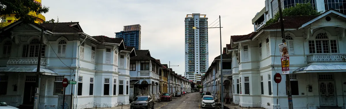 Scenic view of a Penang street with colonial architecture and modern buildings on a cloudy day.