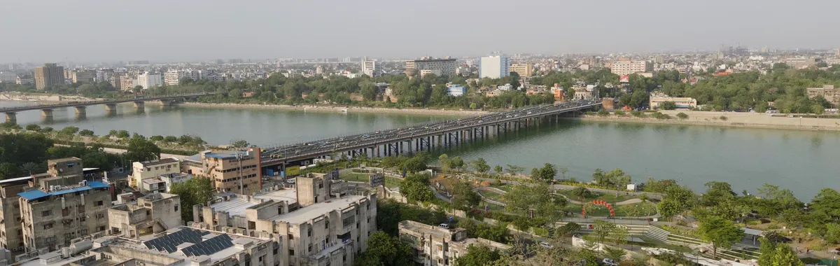 Aerial view of Ahmedabad showcasing the Sabarmati River and city skyline under a clear sky.