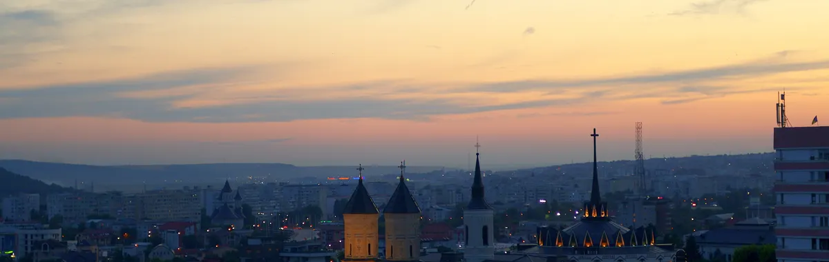 Dusk skyline of Iași with historic church architecture and glowing city lights.